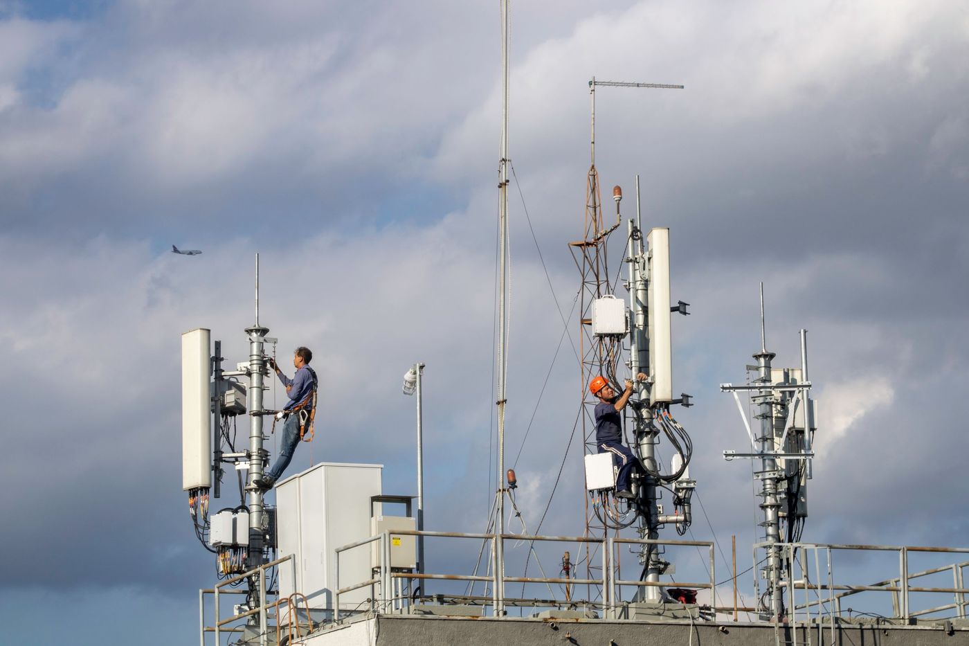 A technician working at height on a rooftop telecom site, among sector antennas and radio links.